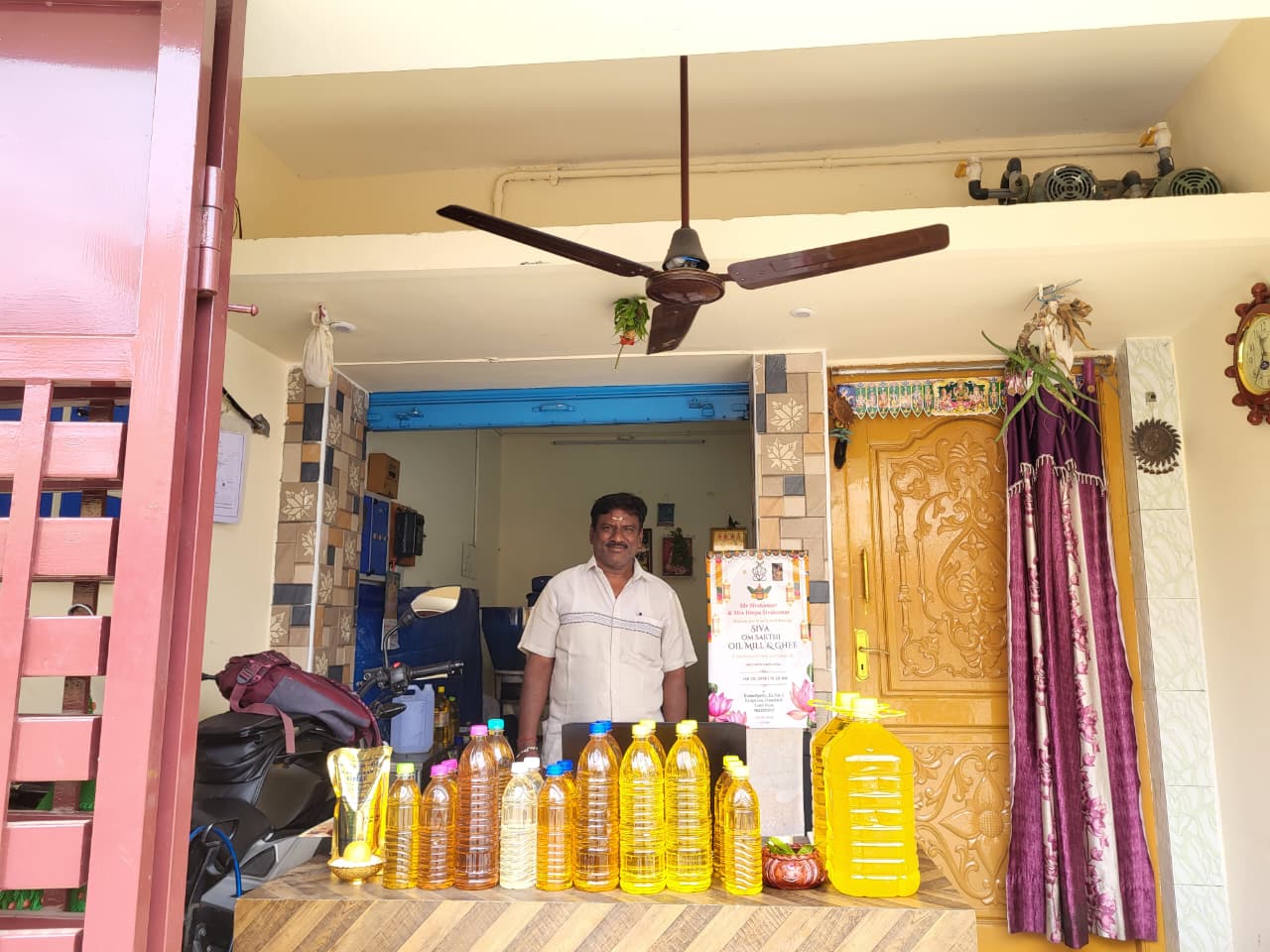 Sivakumar at our Rasipuram mill, with a proposed signboard and labelled bottles; his original photograph is preserved